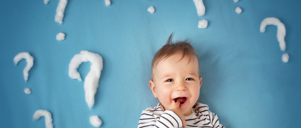 funny little boy lying on blue blanket with lots of question marks