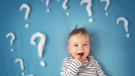 funny little boy lying on blue blanket with lots of question marks
